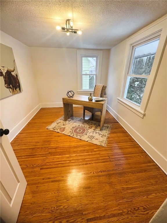 home office featuring hardwood / wood-style floors, a textured ceiling, and a notable chandelier