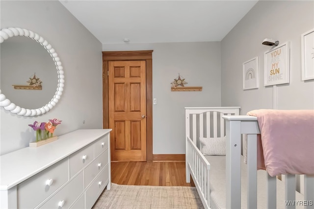 bedroom featuring a nursery area and light wood-type flooring