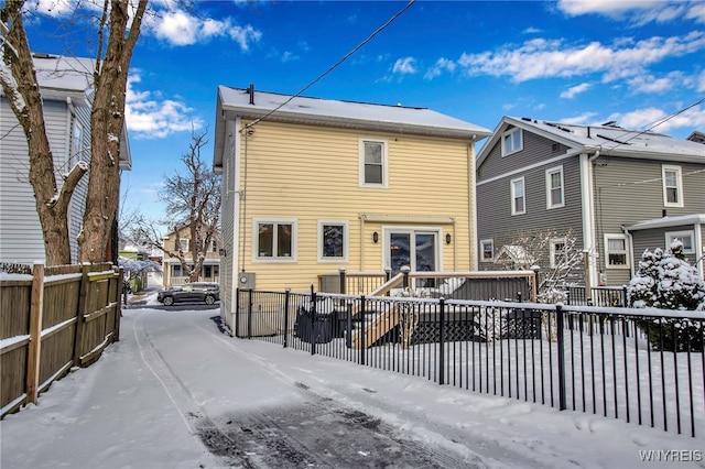 snow covered back of property with a wooden deck