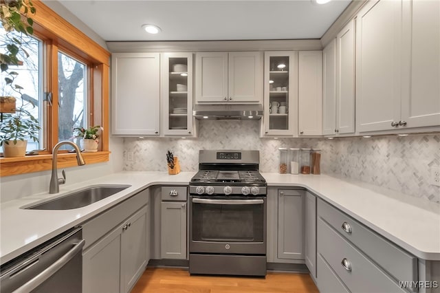 kitchen with appliances with stainless steel finishes, sink, gray cabinetry, and light wood-type flooring