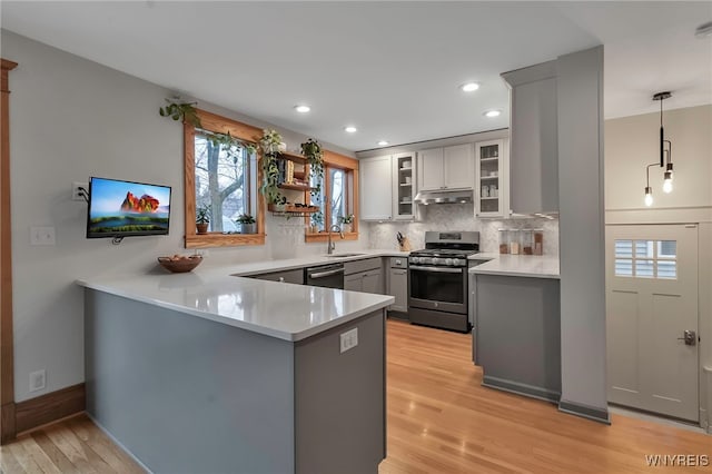 kitchen featuring sink, gray cabinetry, hanging light fixtures, stainless steel appliances, and kitchen peninsula