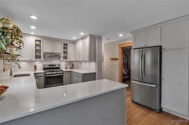 kitchen featuring sink, decorative backsplash, light hardwood / wood-style flooring, and stainless steel appliances