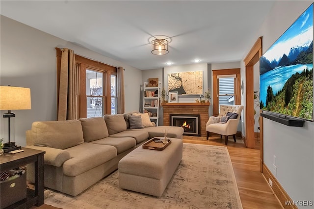 living room with a brick fireplace and light hardwood / wood-style flooring