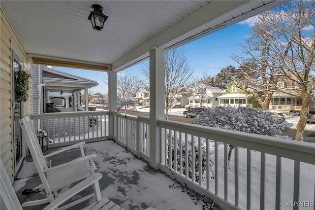 snow covered back of property with a porch