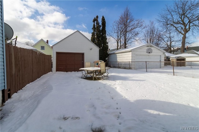 snowy yard featuring a garage and an outdoor structure