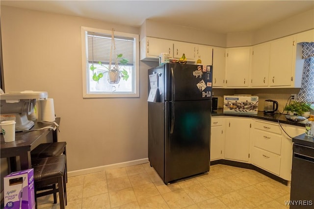 kitchen with white cabinetry, tasteful backsplash, and black fridge