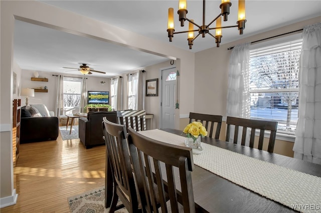 dining space featuring ceiling fan with notable chandelier and light hardwood / wood-style floors