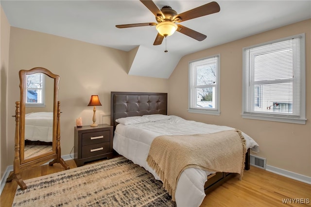 bedroom with vaulted ceiling, ceiling fan, light hardwood / wood-style floors, and multiple windows