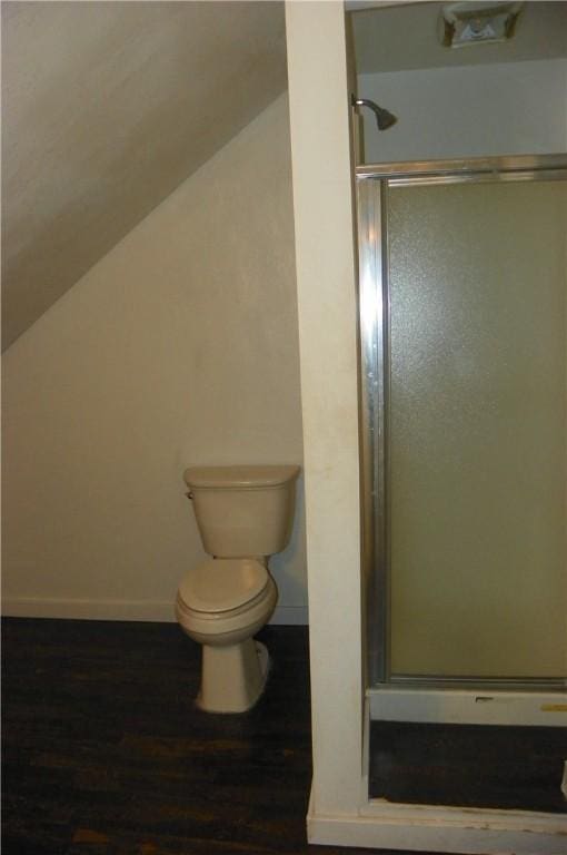 bathroom featuring hardwood / wood-style flooring, lofted ceiling, toilet, and a shower with door