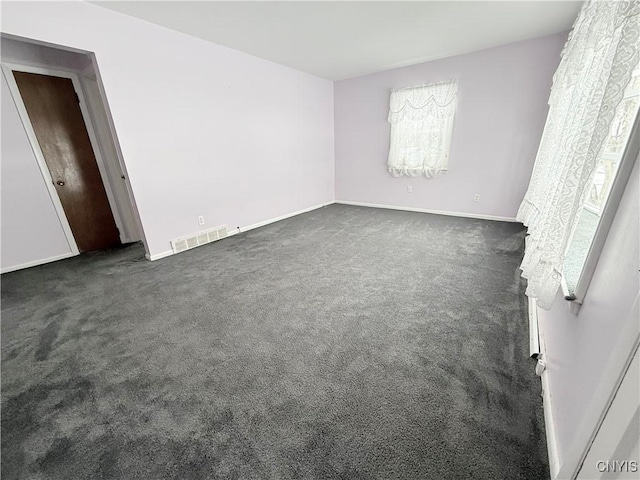 spare room featuring dark colored carpet