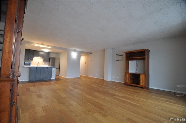 unfurnished living room featuring sink and light wood-type flooring