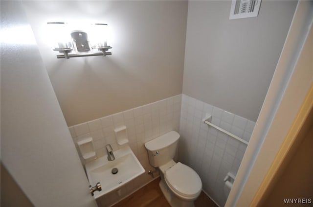 bathroom featuring sink, tile walls, and toilet