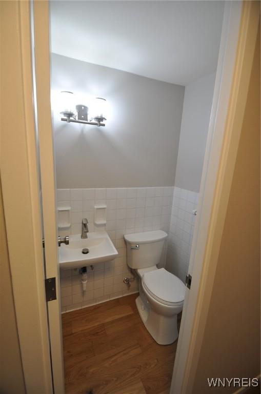 bathroom featuring hardwood / wood-style flooring, toilet, sink, and tile walls