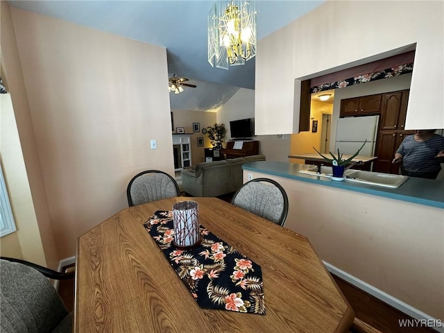 dining room featuring ceiling fan with notable chandelier, lofted ceiling, sink, and wood-type flooring