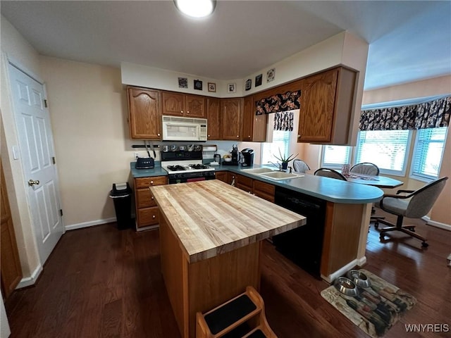 kitchen featuring sink, dark wood-type flooring, black dishwasher, gas stove, and a kitchen island