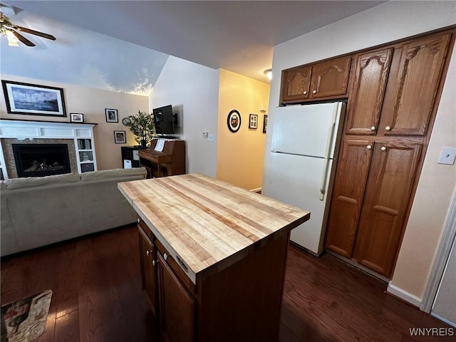 kitchen featuring a premium fireplace, ceiling fan, dark hardwood / wood-style floors, white refrigerator, and vaulted ceiling