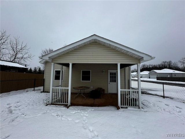 snow covered back of property with covered porch