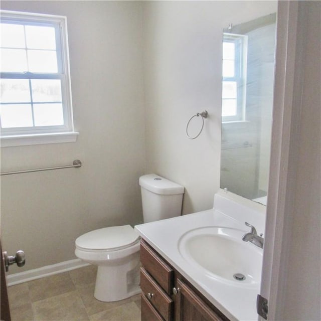 bathroom with baseboards, plenty of natural light, vanity, and toilet