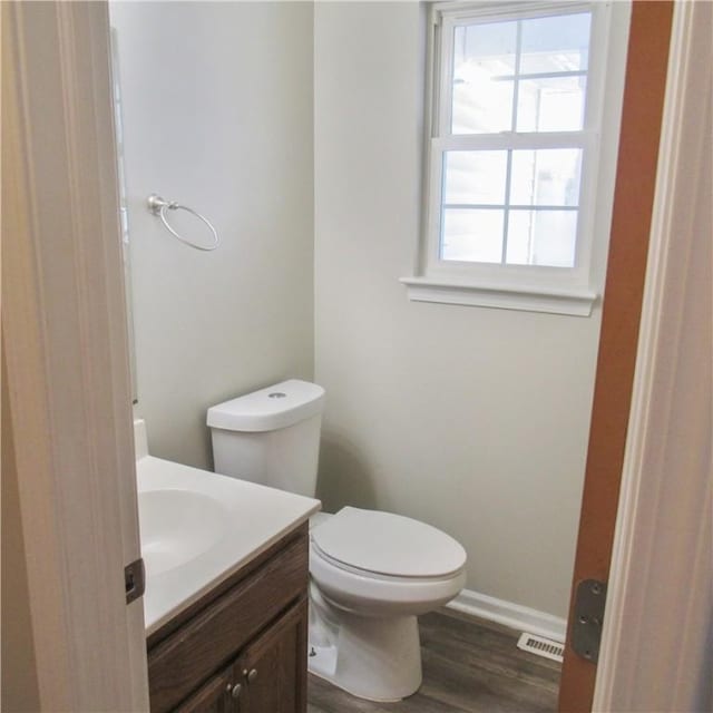 bathroom with baseboards, visible vents, toilet, wood finished floors, and vanity