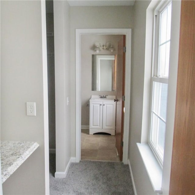 hall featuring carpet flooring and baseboards