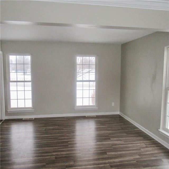 unfurnished room with dark wood-style floors, visible vents, and baseboards