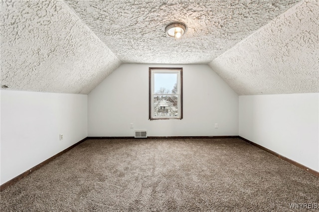 bonus room featuring vaulted ceiling, a textured ceiling, and carpet flooring