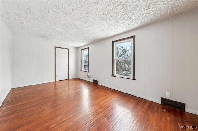 unfurnished room with wood-type flooring and a textured ceiling