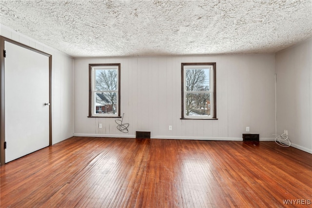 unfurnished room with hardwood / wood-style flooring and a textured ceiling