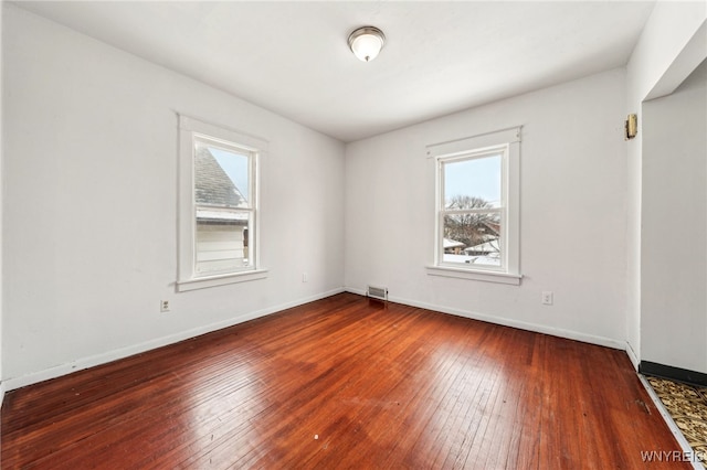 unfurnished room with a healthy amount of sunlight and hardwood / wood-style floors