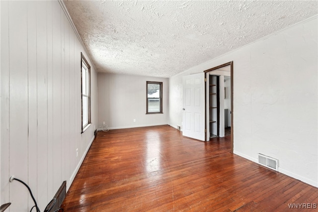 empty room with dark wood-type flooring and a textured ceiling