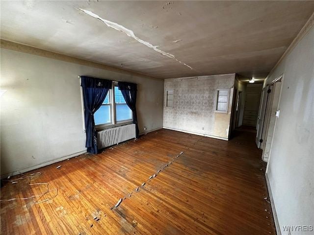 empty room with radiator heating unit and hardwood / wood-style floors