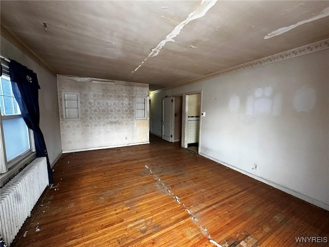 unfurnished room with hardwood / wood-style flooring and radiator heating unit