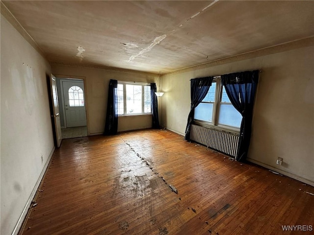 empty room featuring radiator heating unit and hardwood / wood-style floors