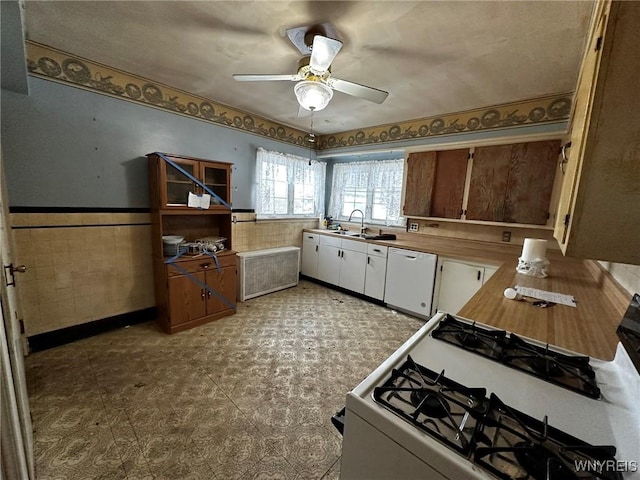 kitchen featuring ceiling fan, white appliances, sink, and tile walls