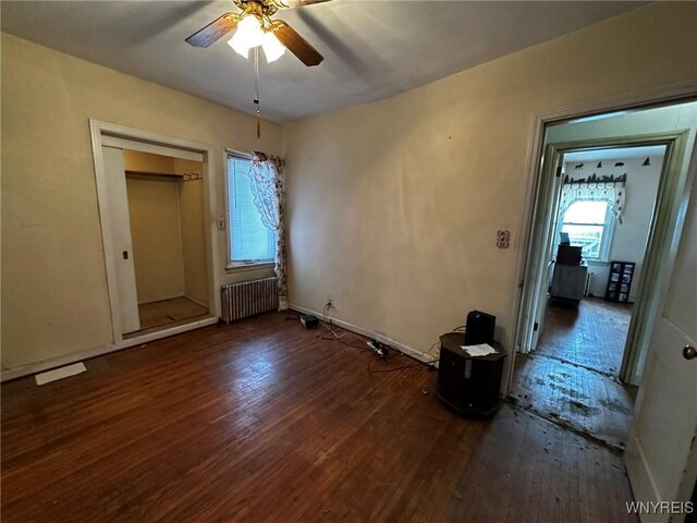 unfurnished bedroom with ceiling fan, radiator heating unit, and dark hardwood / wood-style floors