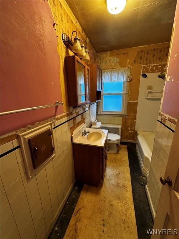 bathroom featuring a tub to relax in, vanity, toilet, and tile walls