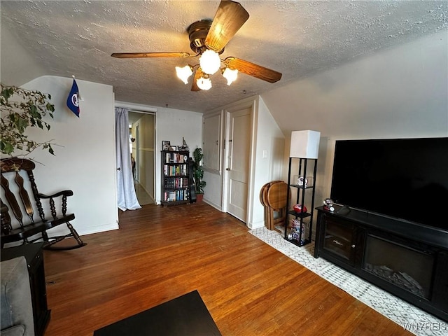 living room featuring lofted ceiling, hardwood / wood-style floors, a textured ceiling, and ceiling fan