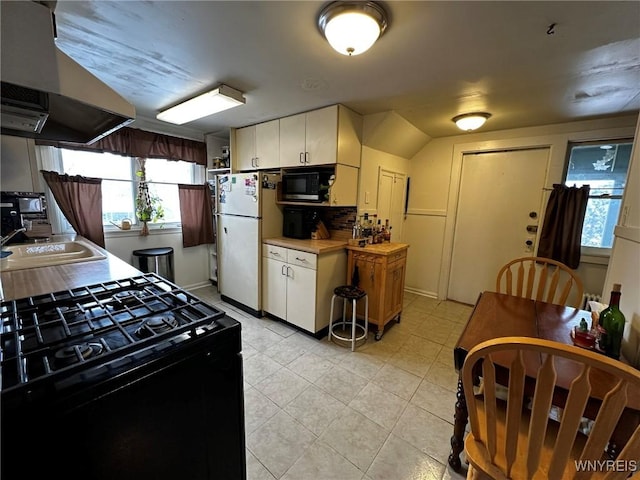 kitchen featuring sink, black range with gas stovetop, white cabinets, and white fridge