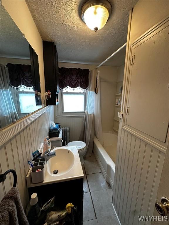 full bathroom with radiator heating unit, a textured ceiling, tile patterned floors, toilet, and shower / bath combo with shower curtain