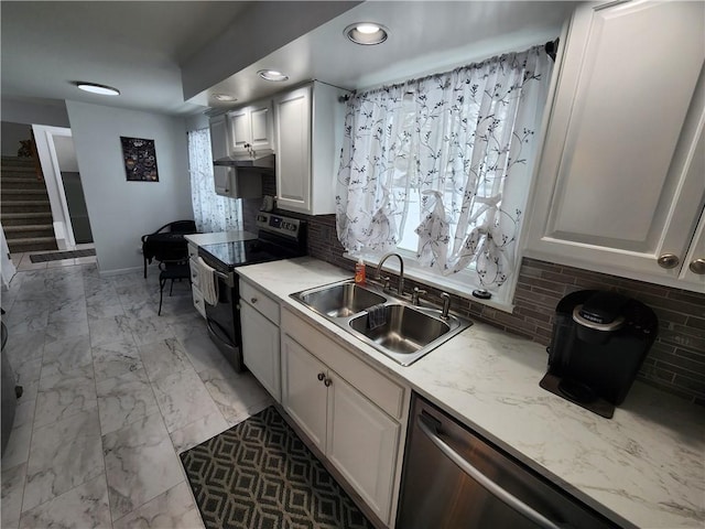 kitchen featuring appliances with stainless steel finishes, sink, white cabinets, backsplash, and light stone countertops