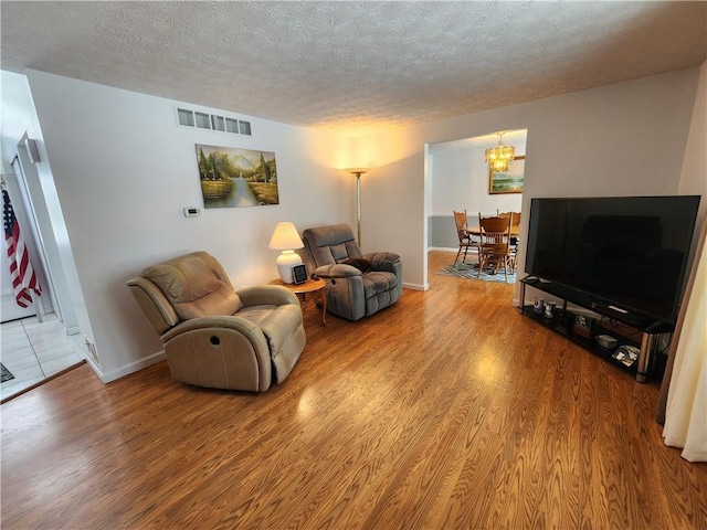 living room with a notable chandelier, wood-type flooring, and a textured ceiling