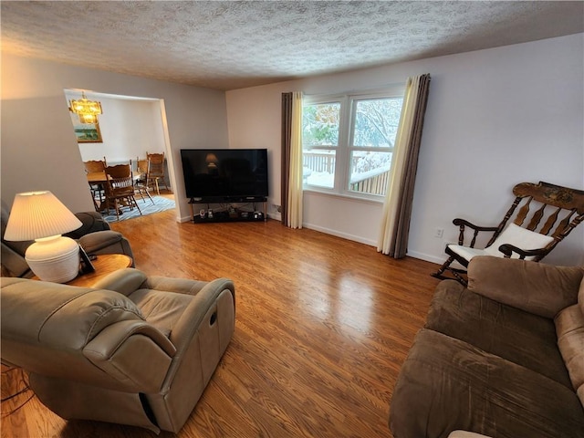 living room with hardwood / wood-style flooring, a textured ceiling, and a notable chandelier