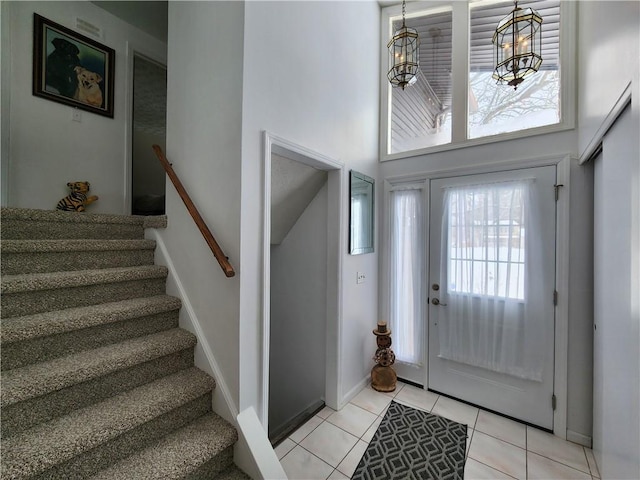 tiled foyer with a towering ceiling and a chandelier