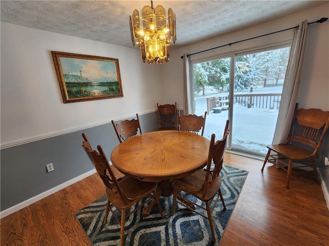 dining room with wood-type flooring, a textured ceiling, and an inviting chandelier