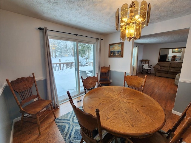 dining room with wood-type flooring, an inviting chandelier, and a textured ceiling