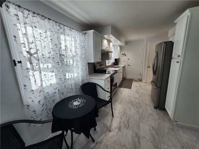 kitchen with stainless steel appliances, white cabinetry, sink, and backsplash