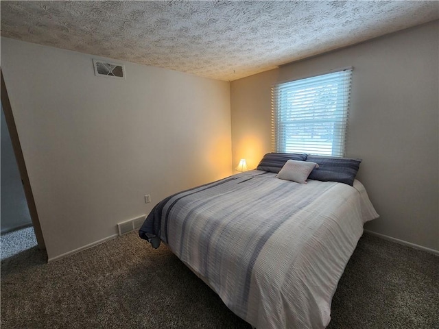 bedroom with a textured ceiling and dark colored carpet