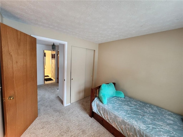 carpeted bedroom featuring a textured ceiling and a closet