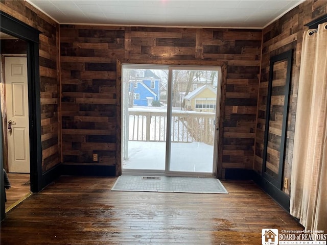 doorway featuring wooden walls and dark hardwood / wood-style floors