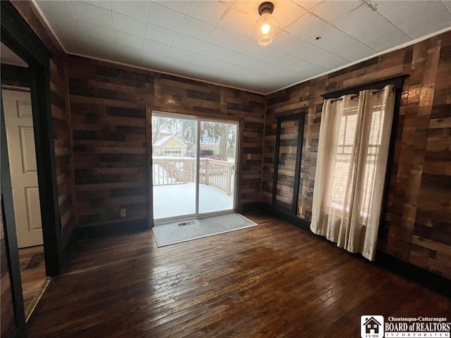 spare room featuring dark hardwood / wood-style floors and wood walls